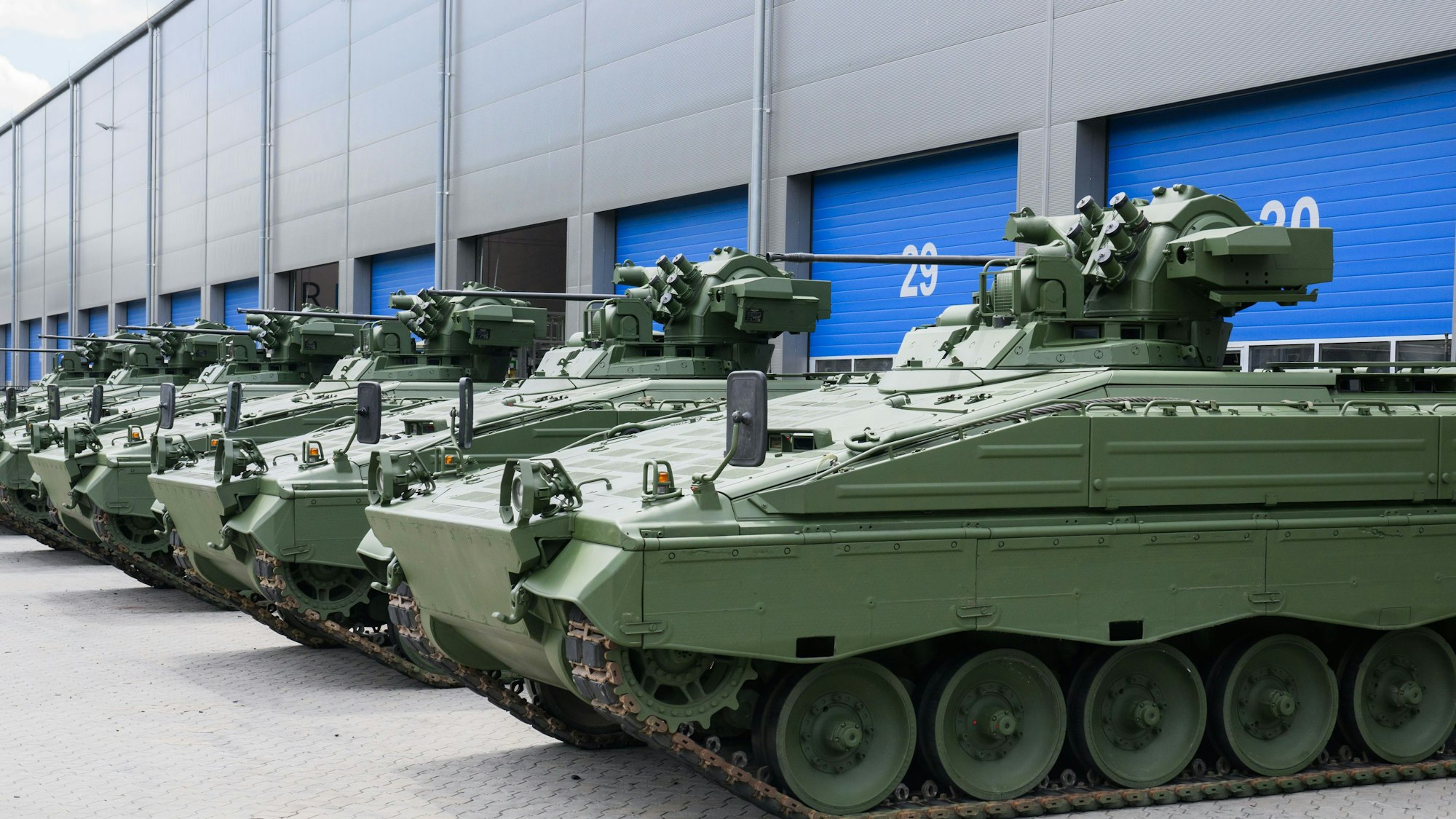 Wieder aufbereitete Marder-Schützenpanzer stehen vor einer Rheinmetall-Halle.