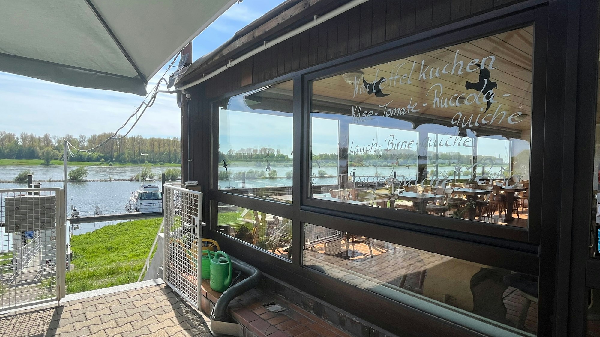 Auf der Fensterscheibe des Hafencafés in Hitdorf werden Gerichte angepriesen.