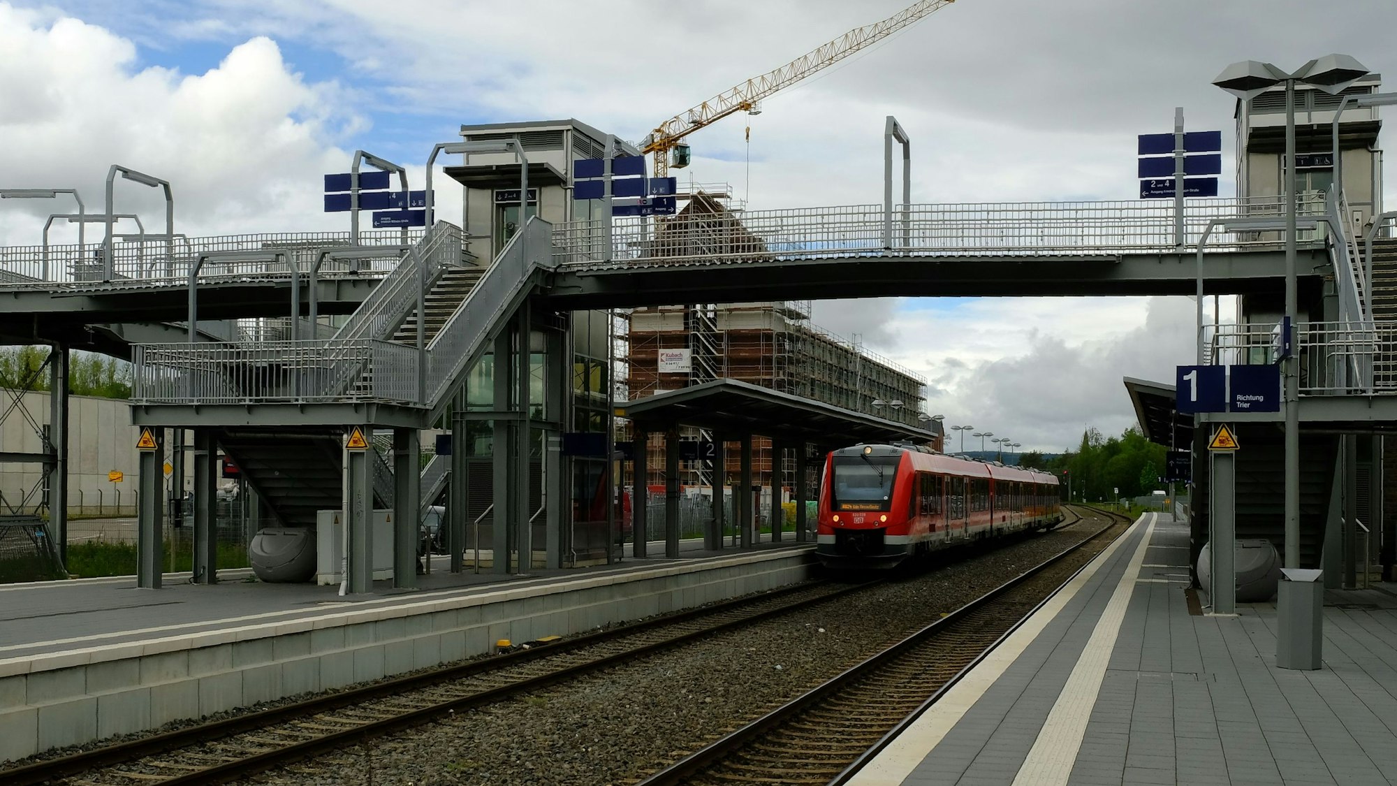 Der Blick auf die Fußgängerbrücke im Mechernicher Bahnhof, in dem ein Regionalzug hält.