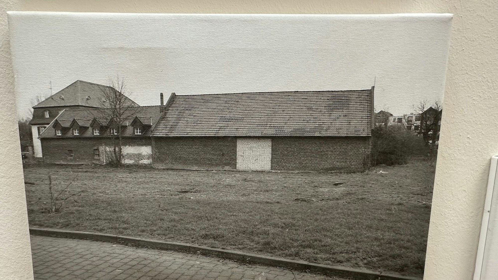Eine Schwarz-Weiß-Fotografie zeigt einen Hof mit Herrenhaus, Stallungen und Scheune.