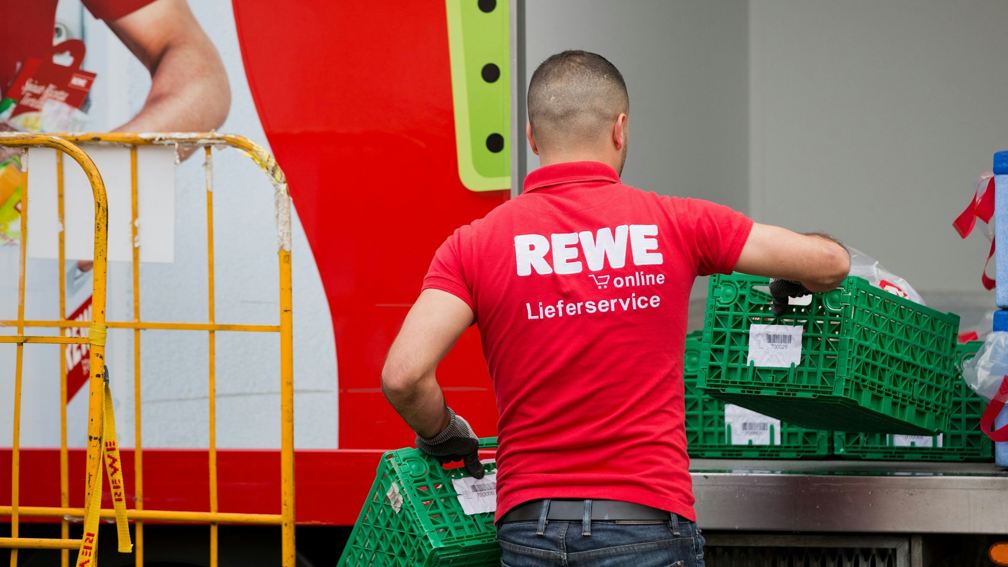 Ein Mitarbeiter von Rewe Online packt am 04.07.2013 vor einem Markt in Köln (Nordrhein-Westfalen) Einkaufswagen in einen Lieferwagen. Die Rewe Group bietet einen Lieferservice für Lebensmittel an. Bestellt wird vorher auf www.rewe-online.de. Foto: Rolf Vennenbernd/dpa (zu dpa-KORR: "Der Supermarkt macht Hausbesuch" vom 11.07.2013) ++ +++ dpa-Bildfunk +++