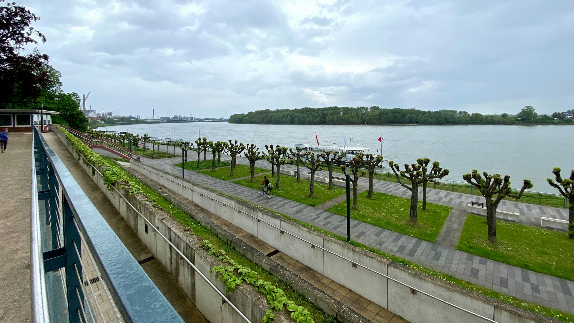 Das Foto zeigt die Uferpromenade in Wesseling und den dahinter liegenden Rhein.
