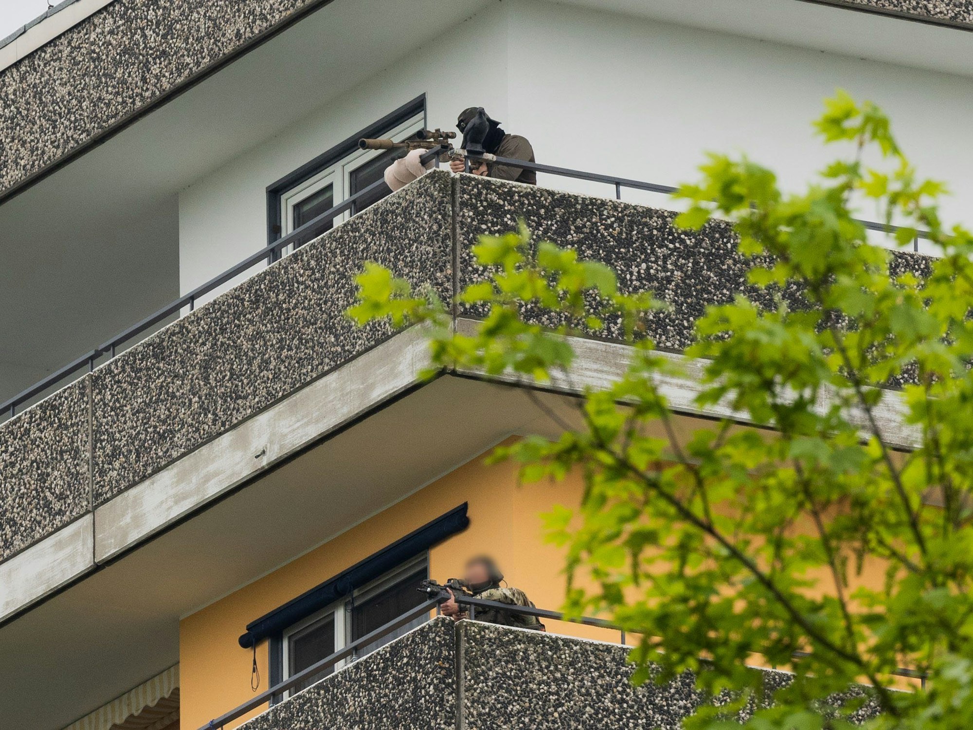 Ein Scharfschützen (oben) und ein weiterer Beamter der Polizei sind auf einem Hochhaus mit ihren Waffen in Stellung gegangen.
