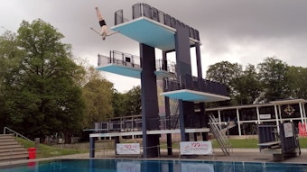 Ein Mann springt vom 10-Meter-Turm ins Wasser.