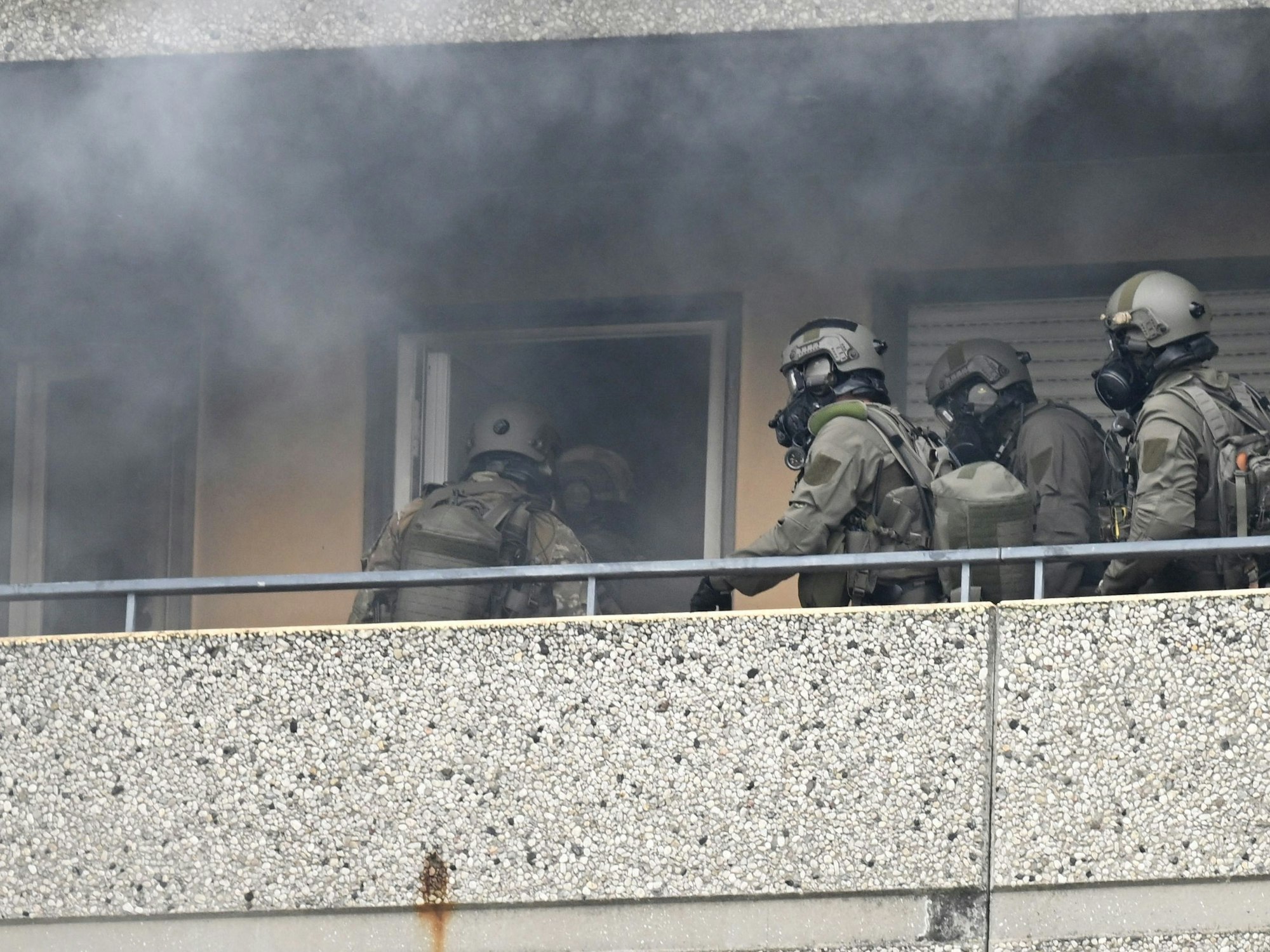 Spezialkräfte der Polizei betreten inmitten von Rauch eine Wohnung in einem Hochhaus.