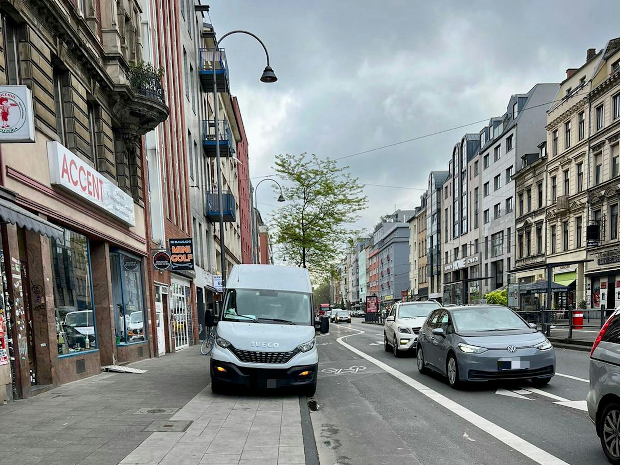Ein Lieferwagen steht vor dem Geschäft Accent auf dem Gehweg der Aachener Straße.