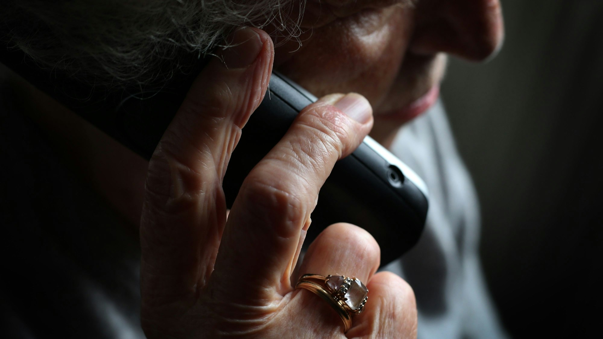 Eine ältere Frau telefoniert mit einem schnurlosen Festnetztelefon.