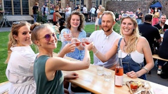 Mehrere junge Menschen prosten sich im Weingarten