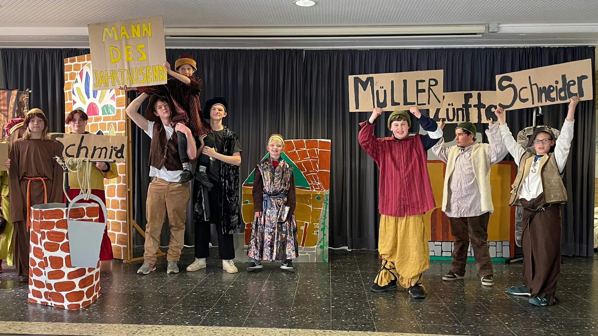 Theateraufführung bei der Feier 50 Jahre Gutenbergschule. Kinderschauspieler und Kinderschauspielerinnen halten Schilder hoch und schauen in die Kamera.