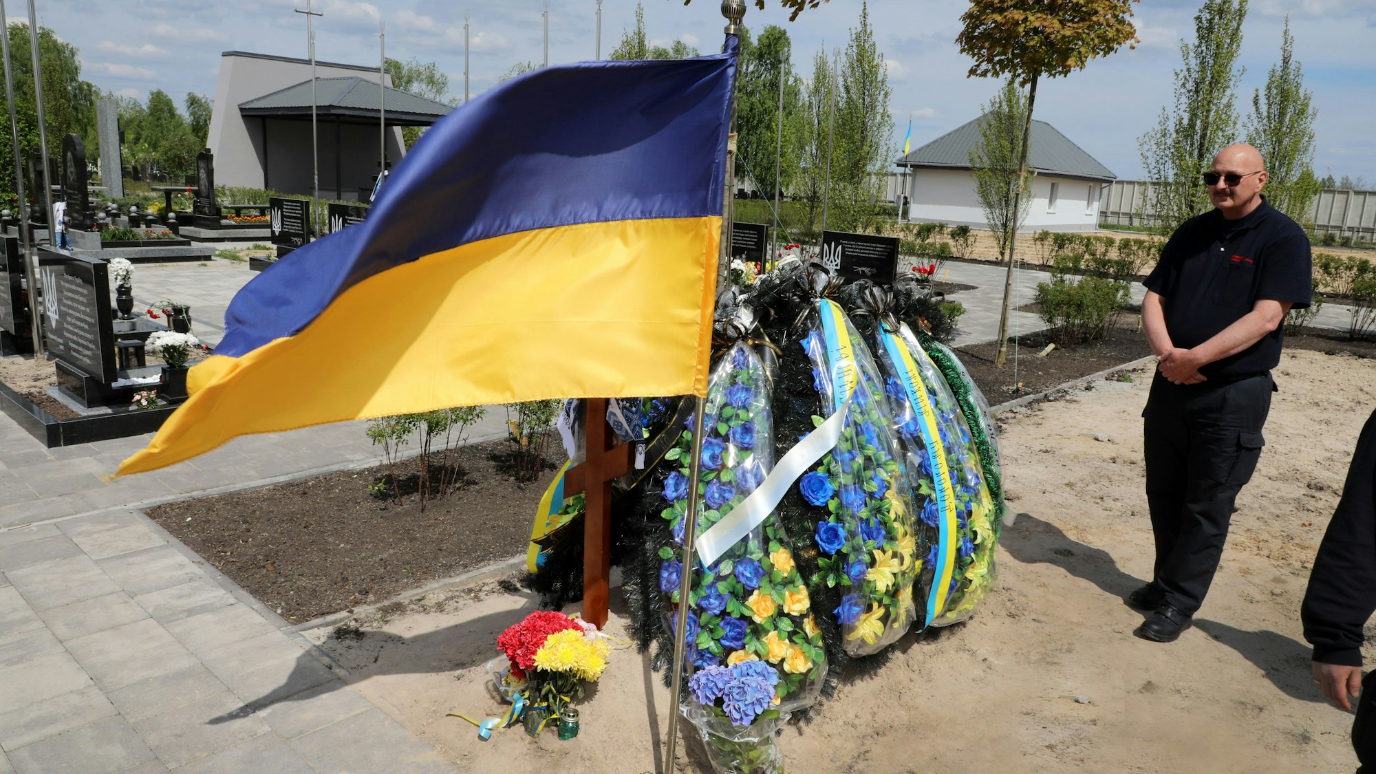 Über einem frisch aufgeschütteten Grab weht eine ukrainische Fahne.