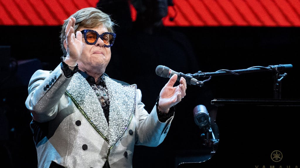 Der Sänger und Pianist Elton John sitzt in der Olympiahalle bei einem Konzert im Rahmen seiner „Farewell Yellow Brick Road Tour 2023“ auf der Bühne.
