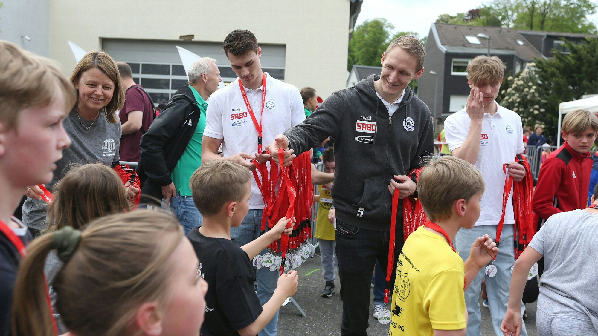 Die Handballer des VfL Gummersbach übergeben bei einem sportlichen Event Medaillen an Kinder.