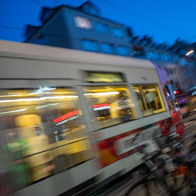 Eine Kölner Stadtbahn fährt über eine Straße am Abend.