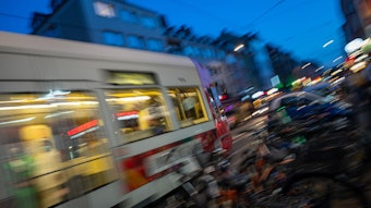 Eine Kölner Stadtbahn fährt über eine Straße am Abend.