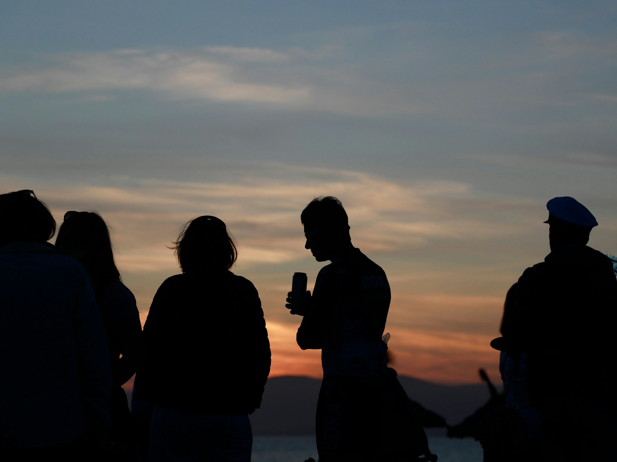 Menschen halten sich während des Sonnenuntergangs am Strand von Arenal auf.