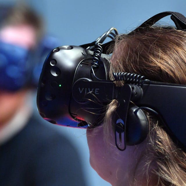 Eine Frau trägt eine VR-Brille, mit deren Hilfe man in eine virtuelle Realität eintauchen kann.