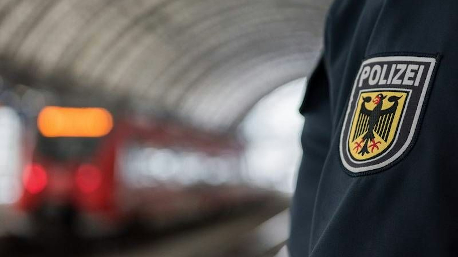 Im Vordergrund ein Ärmel mit Polizei-Abzeichen, im Hintergrund eine Bahn in einem Tunnel.