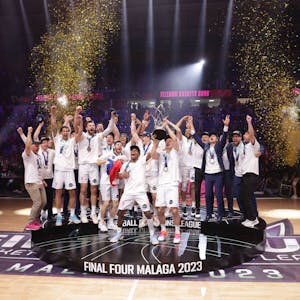 Die Spieler der Telekom Baskets Bonn stehen auf einem Podest und feiern ihren Sieg.
