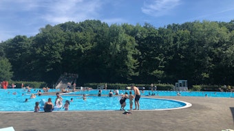 Menschen schwimmen und spielen im Freibad Wiembachtal.