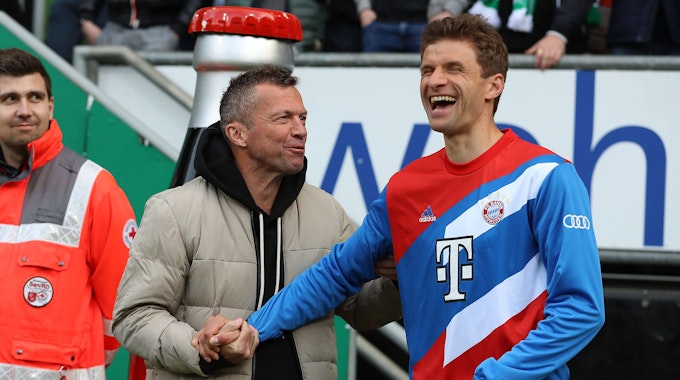 TV-Experte Lothar Matthäus steht im Stadion neben Bayern Münchens Thomas Müller. Beide lachen.