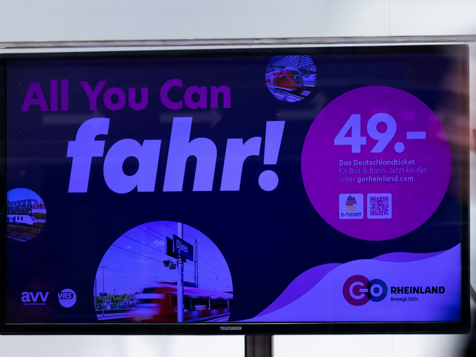 „All you can fahr“ steht auf einem Monitor als Werbung für das Deutschlandticket.