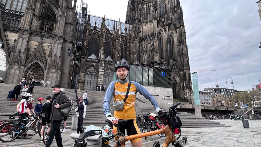 Malte Weber vor dem Kölner Dom mit seinem Fahrrad.