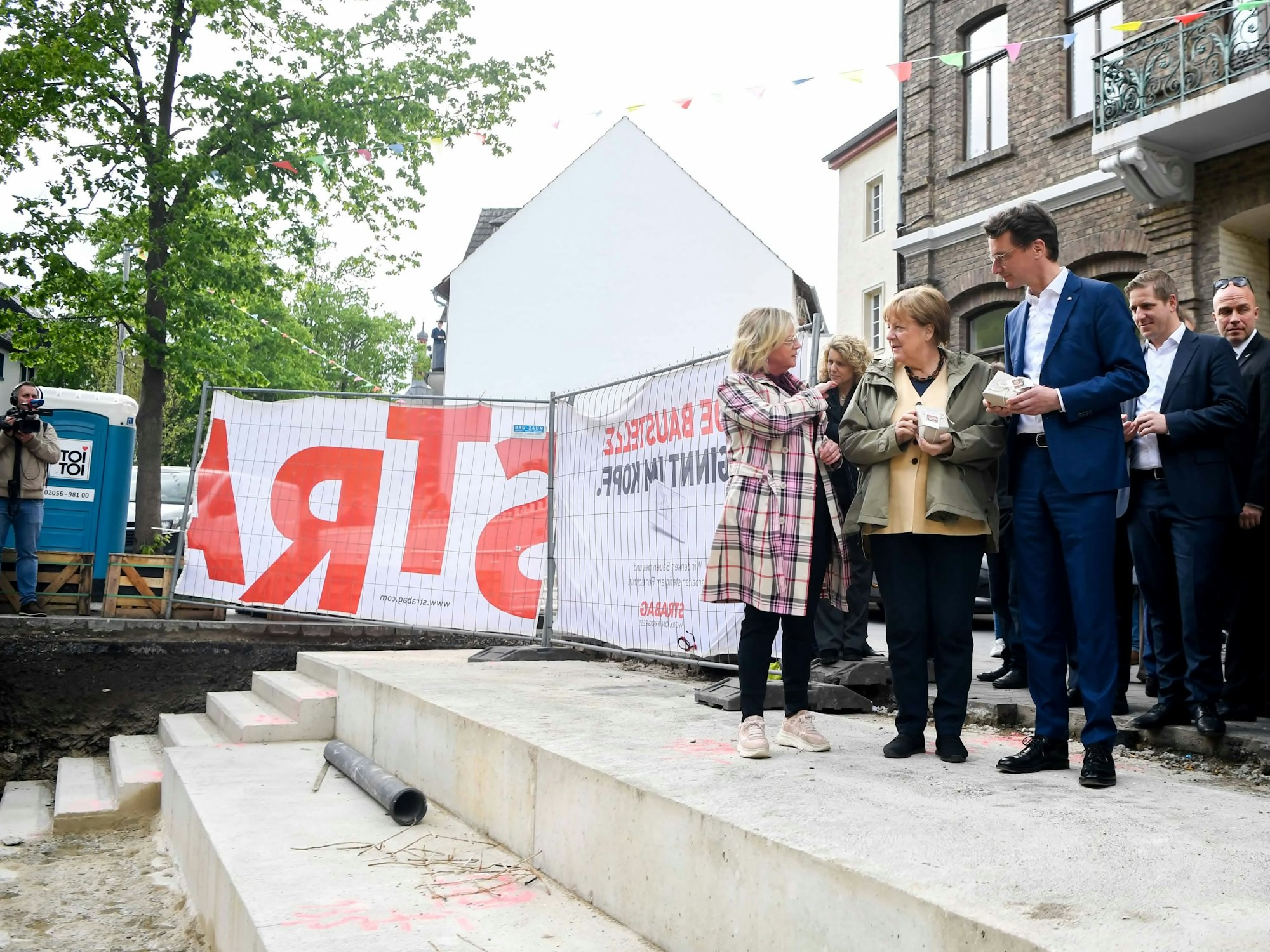 NRW-Ministerpräsident Hendrik Wüst und Ex-Bundeskanzlerin Angela Merkel erhielten von Bad Münstereifels Bürgermeisterin Sabine Preiser-Marian einen bemalten Pflasterstein.