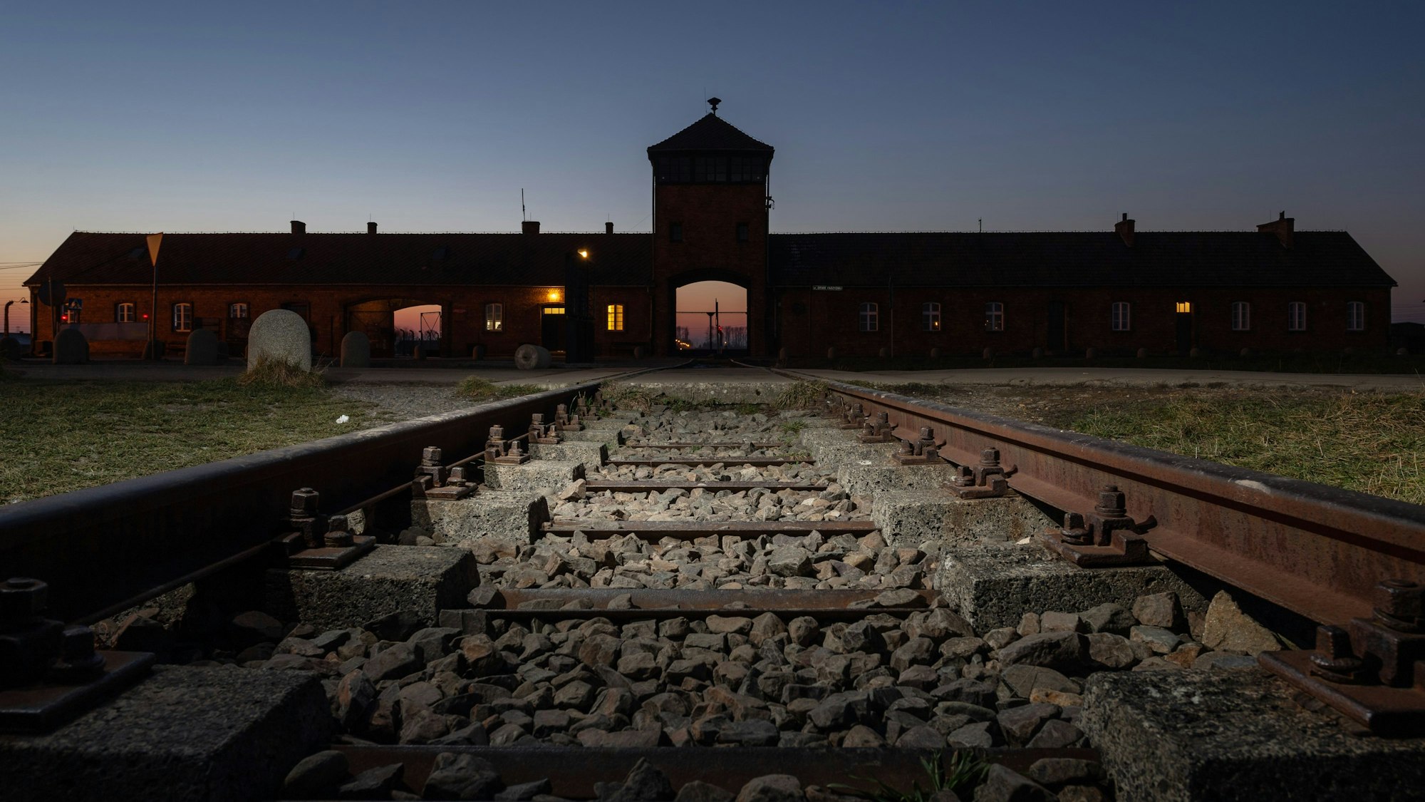 Blick von Eisenbahnschienen auf das Eingangsportal des ehemaligen Konzentrationslagers Auschwitz-Birkenau.