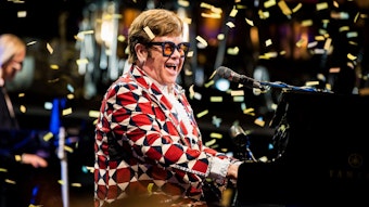 Elton John sitzt am Klavier und es regnet Konfetti.