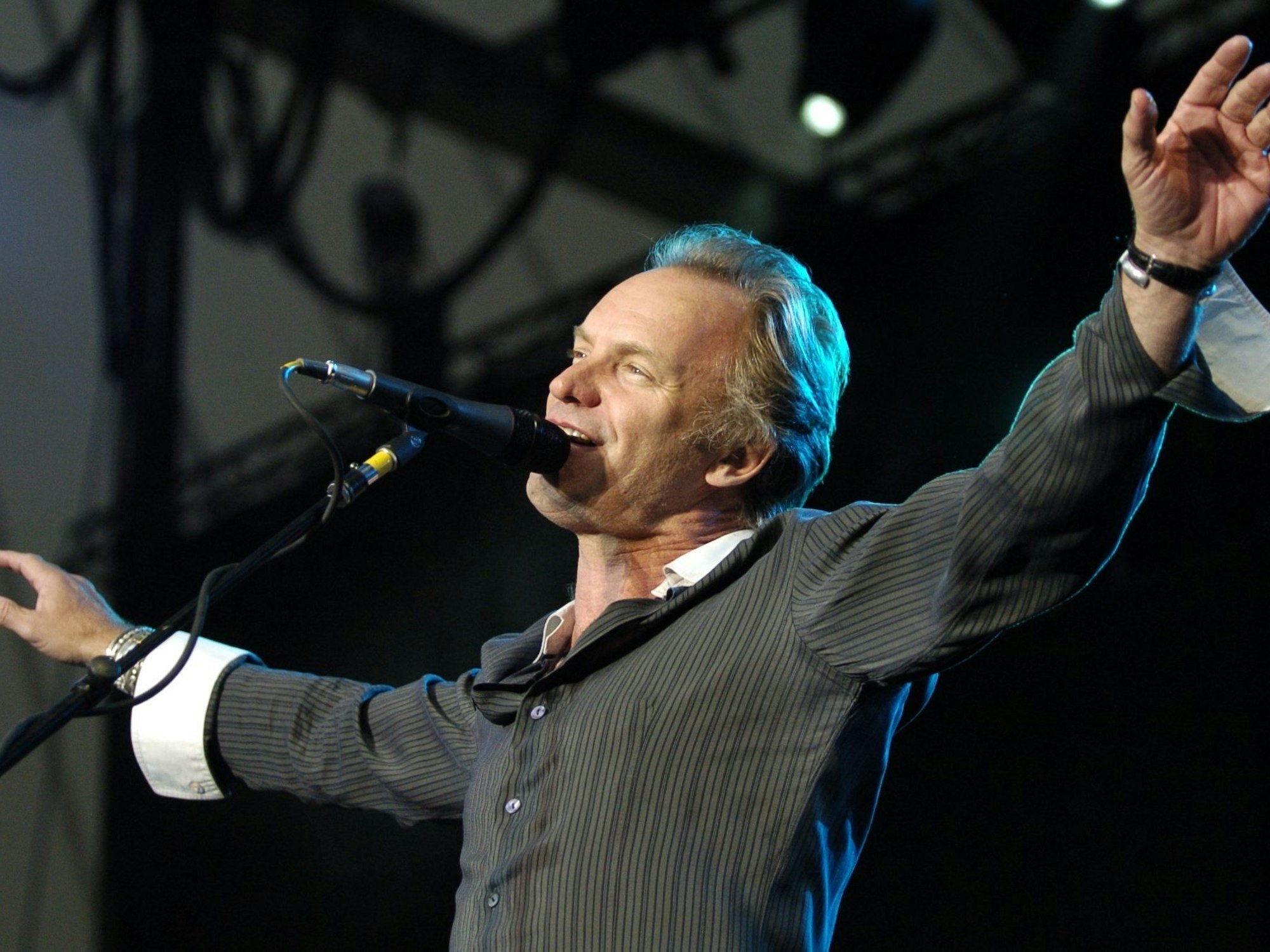 Der britische Popstar Sting hat die Arme beim Singen ausgebreitet.