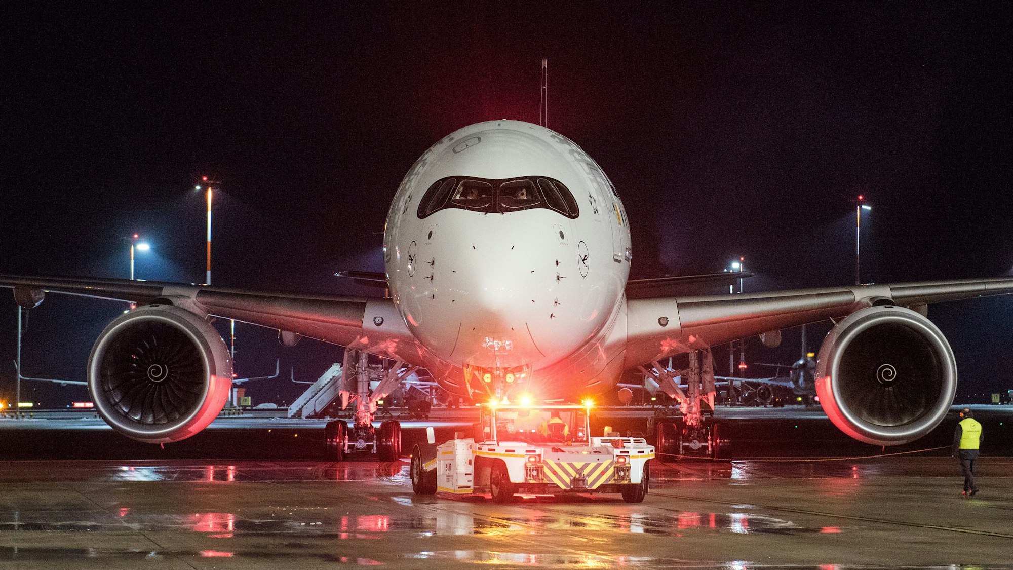 Ein Lufthansa-Flugzeug vom Typ Airbus A350 wird auf einem Rollfeld eines Flughafens in Position gezogen.