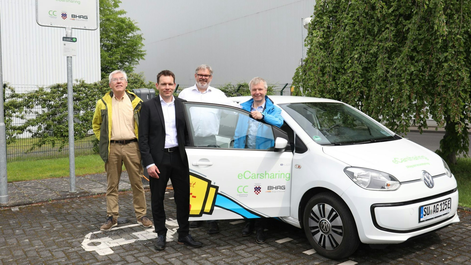 Gerhard Baumeister, Daniel Borchert, Stephan Reuter und Bürgermeister Otto Neuhoff posieren neben einem Elektrofahrzeug.