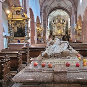 Blick auf den Marmorsarkophag der heiligen Hermann Josef, auf dem einige Äpfel liegen.
