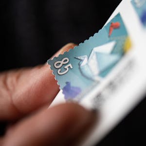 Eine Frau löst eine 85 Cent Briefmarke von einem Bogen. Das jetzige Porto gilt seit Anfang 2022, als sich der Inlandsstandardbrief von 80 auf 85 Cent verteuerte. Das jetzige Porto läuft planmäßig Ende 2024 aus.