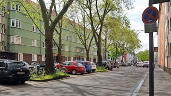 Die Vorgebirgstraße in Köln-Zollstock mit schräg parkenden Autos auf der linken Seite. Auf der rechten Fahrbahnseite soll ein Fahrradschutzstreifen hin.