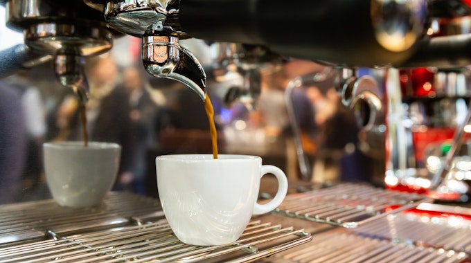 Ein Espresso läuft aus einer Espressomaschine in eine Tasse.