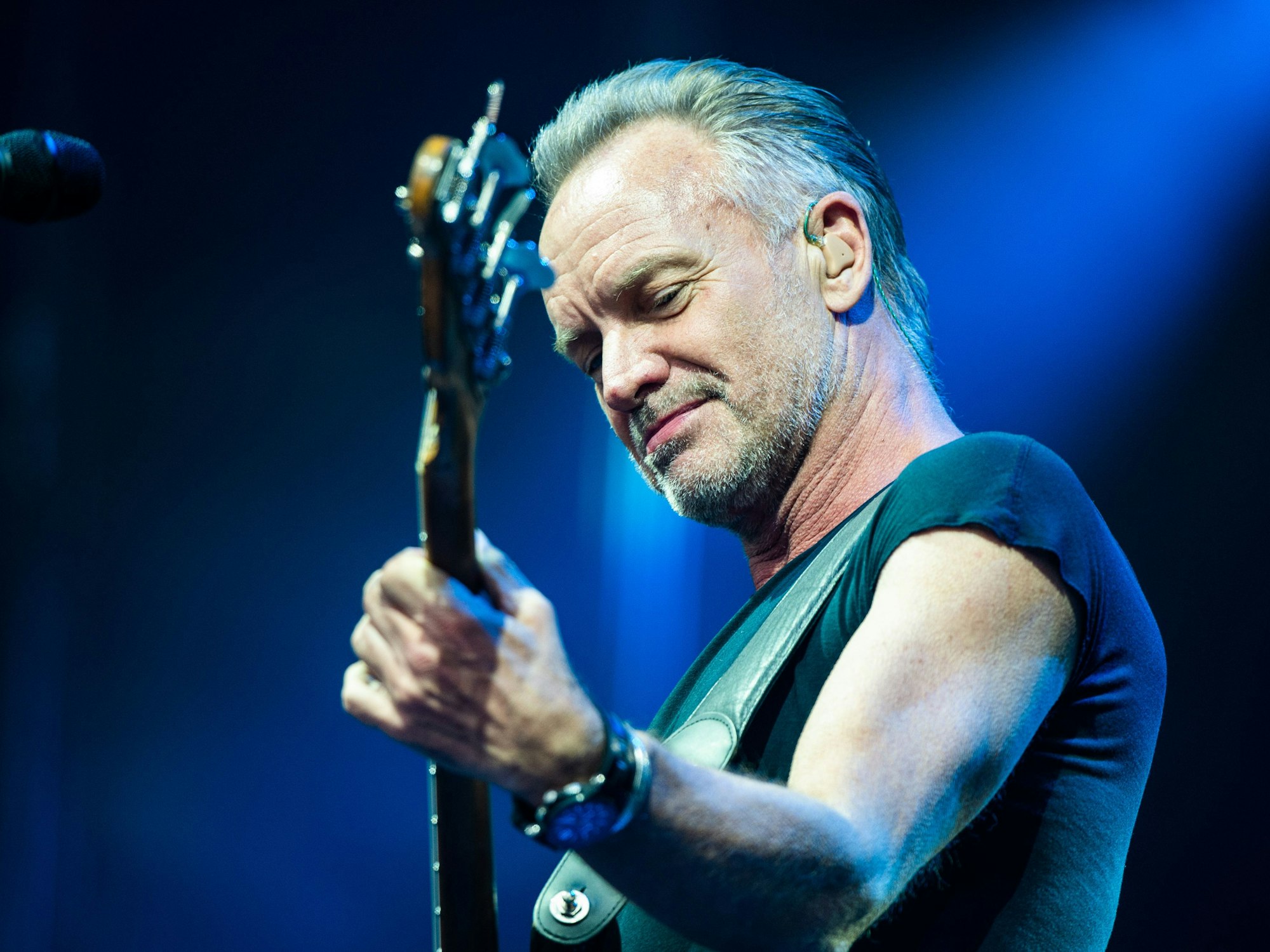 Der Sänger Sting schaut auf die Gitarre.