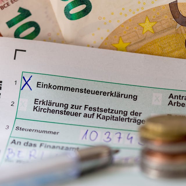 Eine Einkommensteuererklärung und Euro-Münzen liegen auf einem Tisch