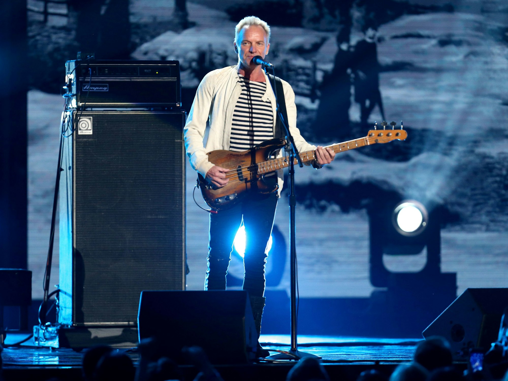 Sting steht mit der Gitarre am Mikrofon.