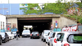 Die Bahnunterführung in Köln-Mülheim mit fahrenden und parkenden Autos.