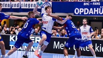 Ein Handballer wird in einer Angriffssituation von zwei Gegenspielern aufgehalten.