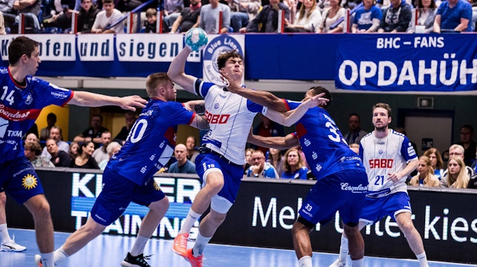 Ein Handballer wird in einer Angriffssituation von zwei Gegenspielern aufgehalten.