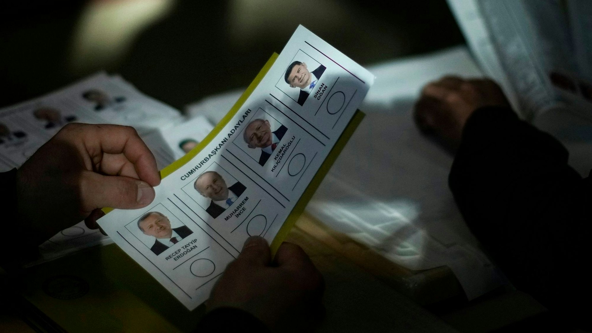 14.05.2023, Türkei, Istanbul: Ein Wahlhelfer hält die Stimmzettel für die Präsidentschaftswahlen mit den Namen von Recep Tayyip Erdogan, Muharrem Ince, Kemal Kilicdaroglu und Sinan Ogan bereit.