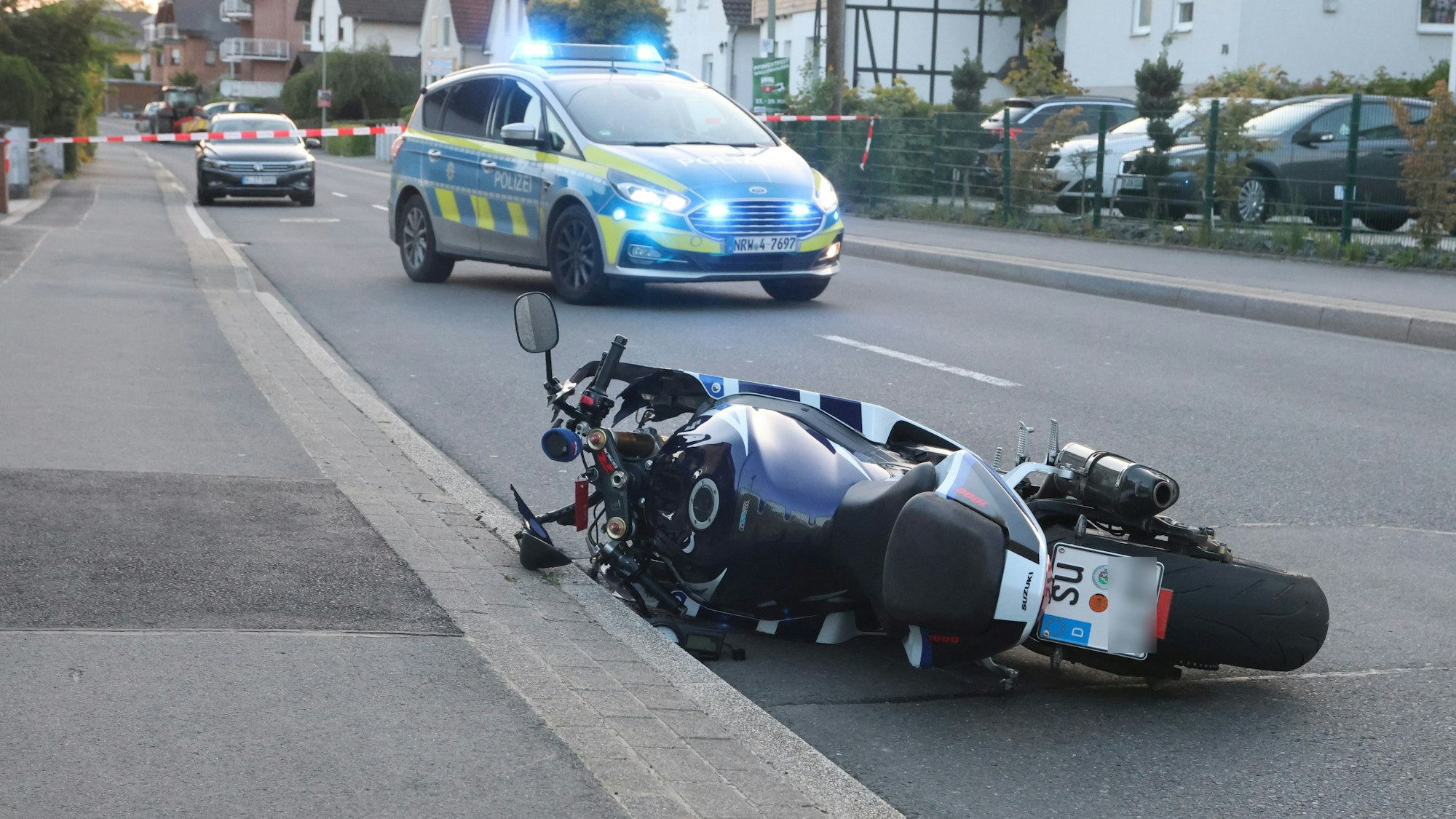 Ein Motorrad liegt auf einer Straße. Im Hintergrund steht ein Polizeiauto.