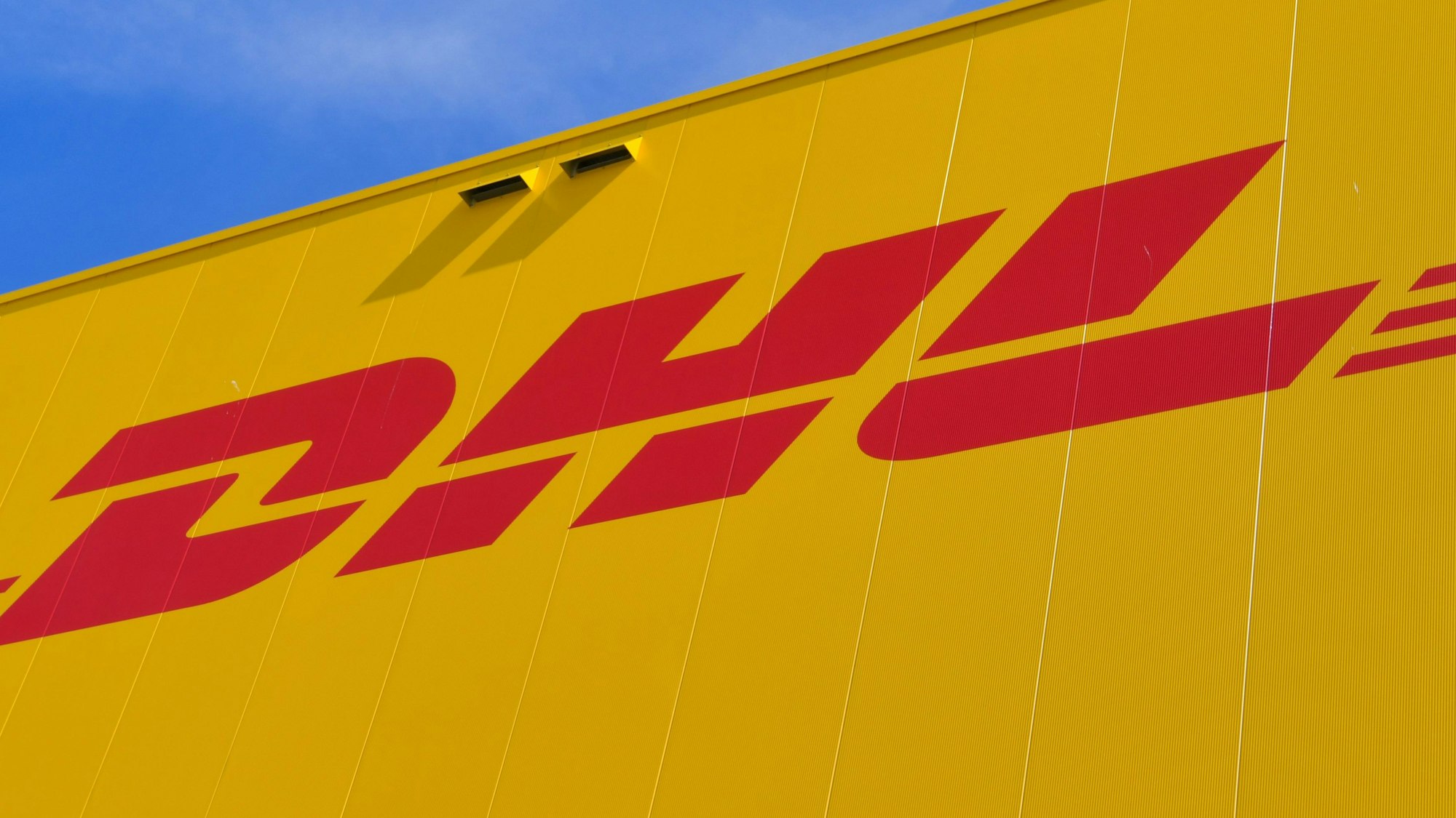 Das Logo des Paketdienstes DHL der Deutschen Post auf der Fassade eines Paketzentrums.