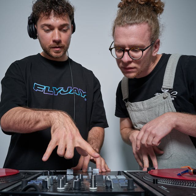 DJ Jason Carter und Student Nils Wiedemeyer schauen auf das DJ-Mischpult.