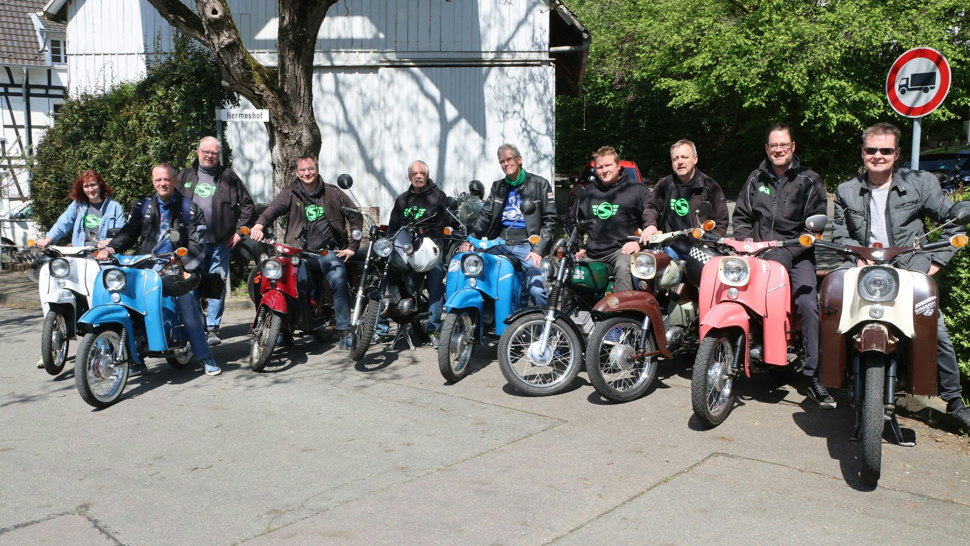 Mehrere Männer und eine Frau stehen mit ihren Simson-Mopeds in einer Reihe.
