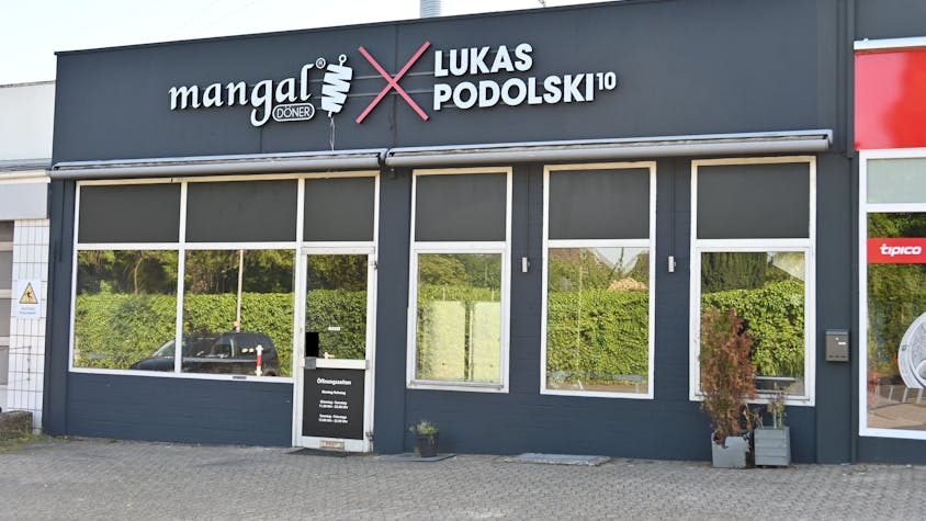 Das Bild zeigt die Filiale von Mangal-Döner in Stommeln. Auf dem dunkelgrauen Gebäude steht in großen Buchstaben "Mangal Döner" und "Lukas Podolski".