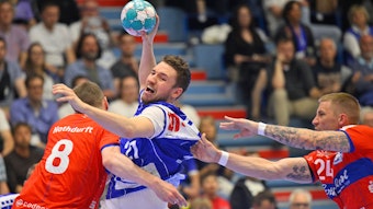 Ein Handballer wird im Angriff von zwei Gegenspielern festgehalten.