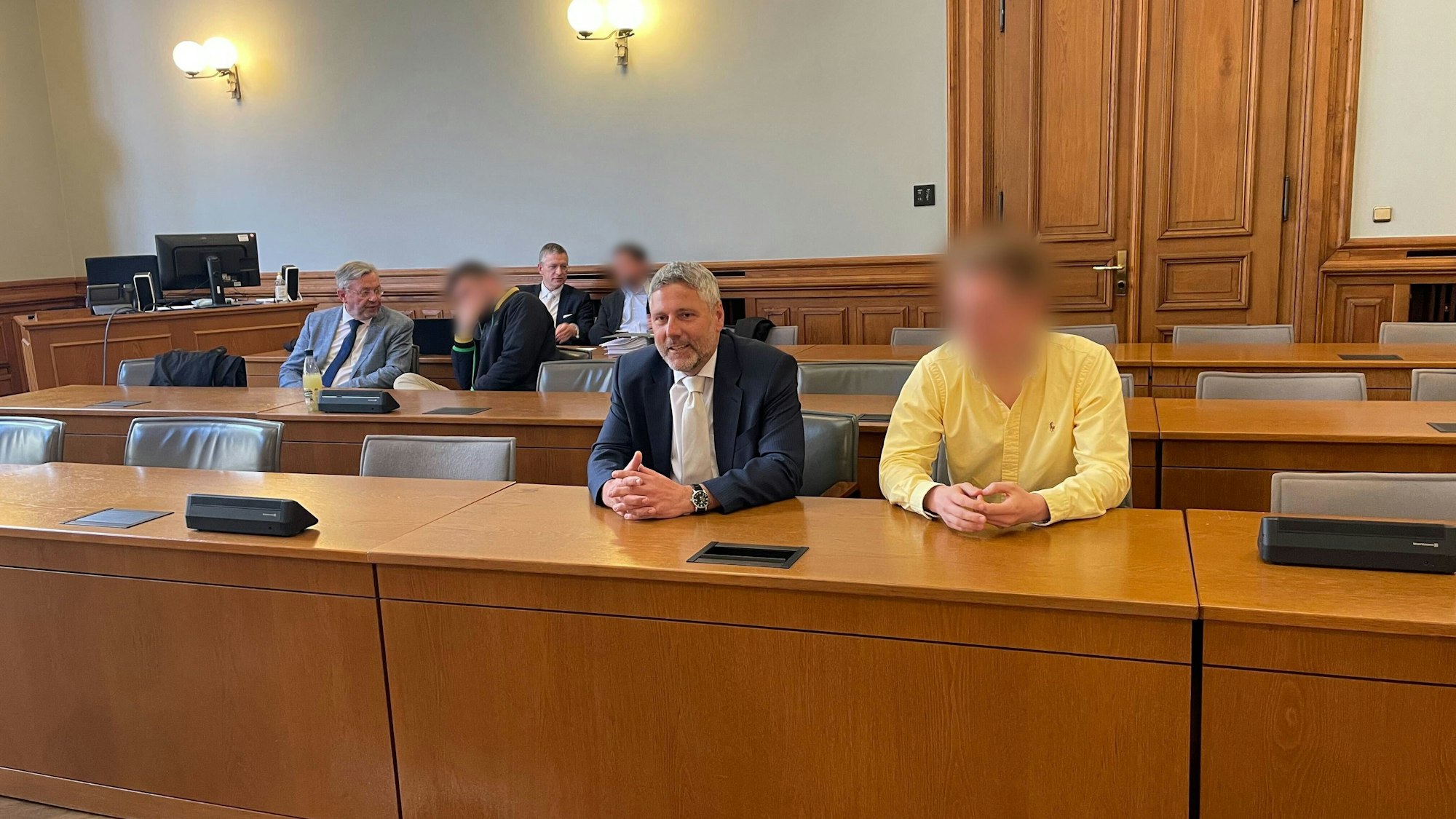 Drei der vier Angeklagten im „Kinderzimmer-Dealer“-Prozess sitzen neben ihren Anwälten in einem Saal vom Landgericht Leipzig.